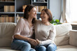 © fizkes - Overjoyed young woman with mature mother chatting, laughing at joke, enjoying pleasant conversation, middle aged mum and grownup daughter hugging, having fun, sitting on cozy couch at home