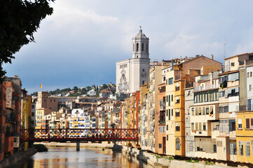 City panorama with a river, a bridge and houses of different colors.