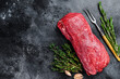 Raw fillet Tenderloin beef meat for steaks with thyme and rosemary. Black background. Top view. Copy space