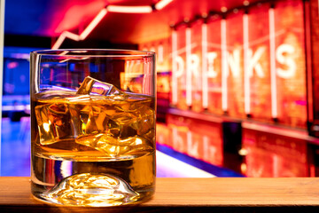 Wall Mural - Glass of whiskey with ice cubes at a night club