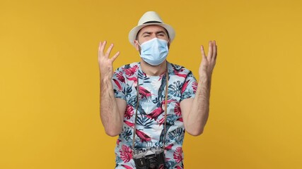 Wall Mural - Shocked traveler tourist man in face mask safe from coronavirus virus isolated on yellow background. Passenger travel on weekend. Air flight journey concept. Put hands on head spreading arms ask why