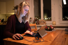 Junge Frau arbeitet abends zuhause im Homeoffice am Laptop
