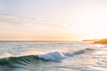 Golden Hour Sunset With Pacific Ocean Waves Crashing Along Cliff Shoreline Of Santa Cruz Bay On California Coast