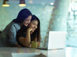 © bongkarn - Sisters hugging while looking on laptop in modern living room