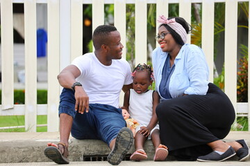 Wall Mural - Family of African American people with young little daughter sitting in front of new house with white picket fence