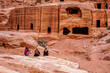 © Angela Meier - Jordan , Petra, Street of Facades, Tombs carved out of the pink Sandstone rock. Local people are sitting in front of the ancient tombs.