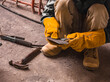 © Mdv Edwards - A man inspects a makeshift scraper or putty knife created onsite with leftover metal parts at a construction site.