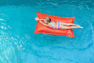 Top view of young baby girl on floating bean bag relaxing in blue swimming pool. Happy family travel background. Healthy lifestyle on summer beach holiday  in luxury spa hotel.