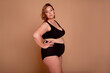© Вероника Зеленина - Overweight  woman with fat body in underwear posing on biege studio bsckgroung ,Concept of body positive