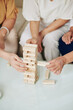 © DragonImages - Close-up image of aged women taking wooden blocks out of tower when playing strategy game at home