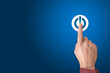 © Celt Studio - Hand of the businessman pressing power button. Start up business concept. Arm press on button on-off. Blue background, copy space