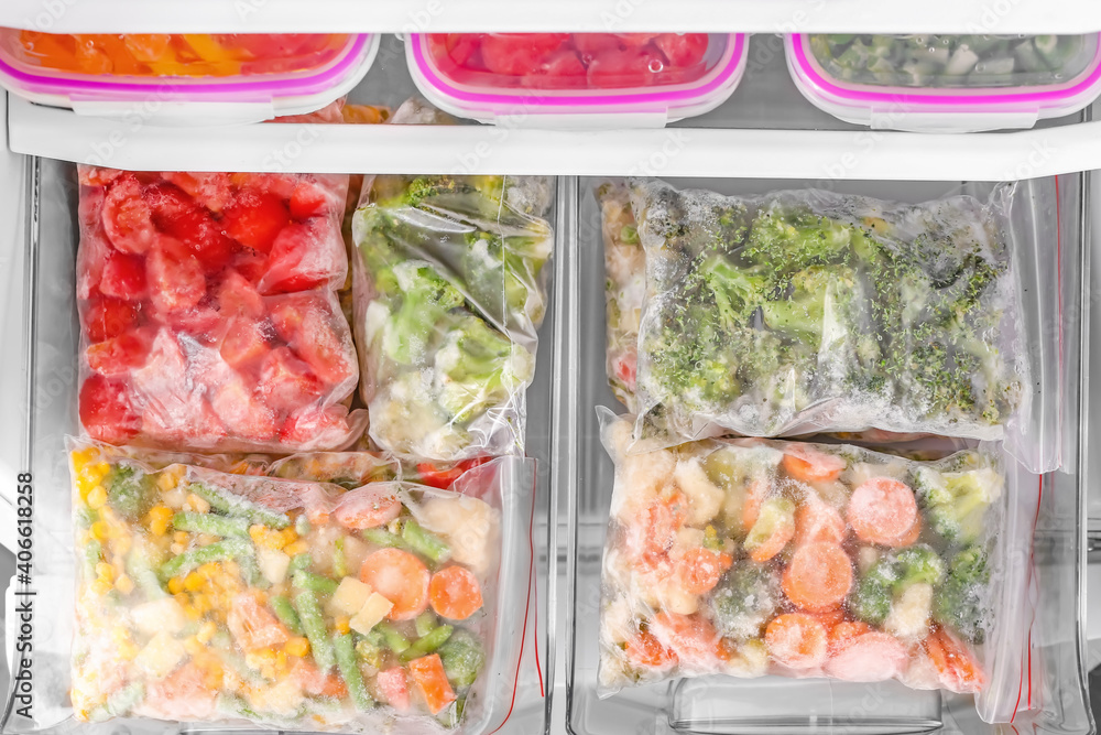 Plastic bags with frozen vegetables in refrigerator