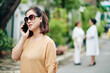 © DragonImages - Portrait of senior woman in sunglasses walking in park and calling on phone