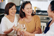 © DragonImages - Group of cheerful Asian senior women drinking white wine at kitchen table and talking about health and family issues