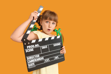 Surprised little girl with movie clapper on color background