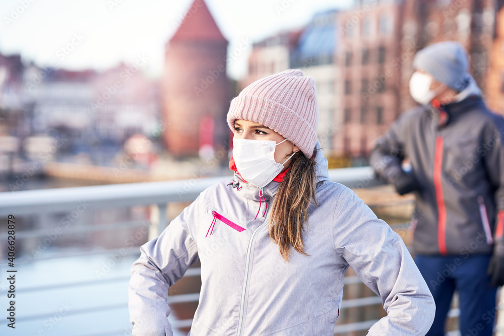 Adult couple jogging in the city in masks during lockdown - obrazy, fototapety, plakaty 