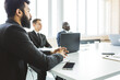 © xartproduction - Group of young business people working and communicating while sitting at the office desk together with colleagues sitting. business meeting