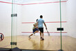 Squash player in action reaching on squash court. Out of focus, possible granularity, motion blur