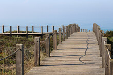 Path Made Of Wooden Roasts, Wooden Bridge Leading To The Blue Horizon Over A Sandy And Overgrown Cliff