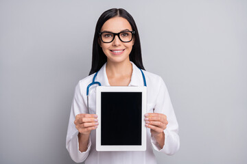 Photo of doctor woman hold tablet show screen empty space wear stethoscope glasses white uniform isolated grey color background