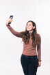 Photo of young woman taking selfie over white wall.