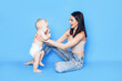 © Anastassiya  - Mom plays in her arms with her son against a blue background. Education and care for the health of children