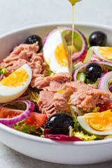 Canvas Print - Tuna salad with egg, olives and vegetables in white bowl, white background. Diet food concept.