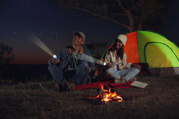 Sticker - Couple with flashlights near bonfire at night. Camping season