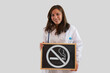 © fabio - Serious female doctor holding blackboard with ban on smoking. Concept of quitting smoking.
