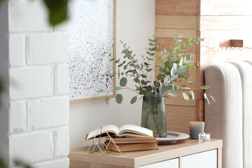 Wall Mural - Beautiful eucalyptus branches and books on cabinet in modern room. Interior design