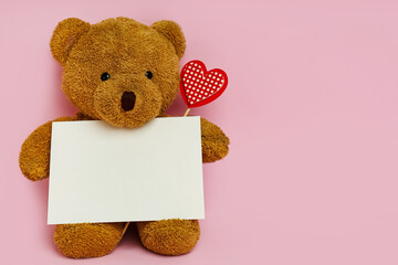 cute teddy bear with red heart and blank card on pink background, space for text. valentine's day ce