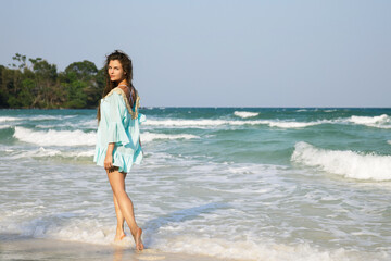 Wall Mural - Young lovely woman is walking by the sea shore