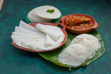 Wall Mural - Chicken curry with pathir and ideyappam,a good combination of chicken curry with nice pathiri ,white pathiri and ideyappam arranged on dark green texture background.