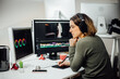 © BASILICOSTUDIO STOCK - Profile view of Female designer sitting, editing video on a computer at her workplace. Modern business woman working concentrated in video design with a pen tablet in a studio. Freelance worker.