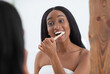 © Prostock-studio - Cheerful young african american female brushing teeth with toothbrush