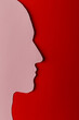 © Marijus - Head silhouette made of paper. Pink paper shaped as a human head with copy space on red paper background.