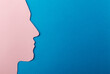 Head silhouette made of paper. Pink paper shaped as a human head with copy space on blue paper background.