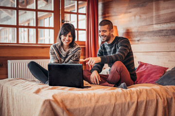 Man and woman at home surfing the net in bed. Couple caucasian lover smiling showing very happy gesture while enjoy using laptop computer together on bed