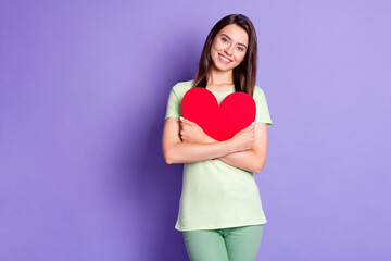 Wall Mural - Photo portrait of cheerful girl wearing green t-shirt hugging embracing heart on valentines day isolated on vibrant purple color background