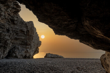Wall Mural - sunrise over the sea as seen from the rock cave