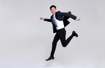 fun portrait of happy energetic young asian businessman jumping in mid-air isolated on studio white 