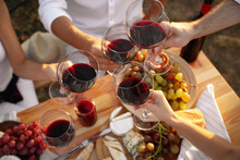 Friends Holding Glasses Of Wine At Table, Closeup