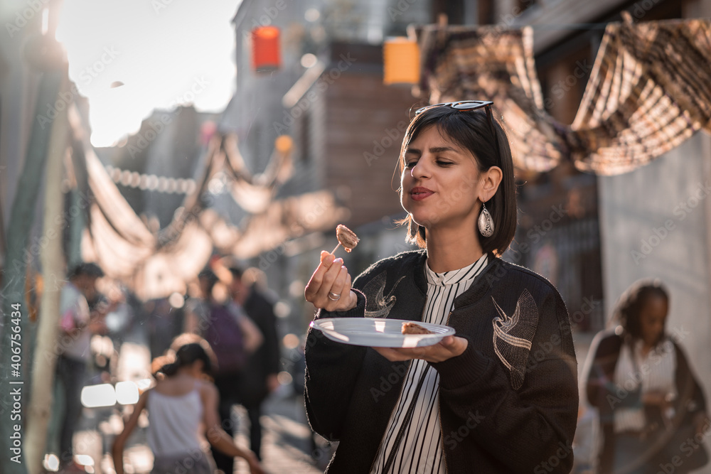 Beautiful young female tourist in city of Paris France enjoying holidays in beautiful little street festival eating street food - obrazy, fototapety, plakaty 