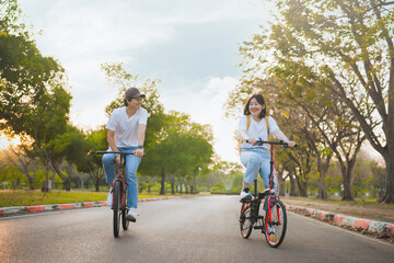 spring is comming concept with happy and cheerful feeling of asian couple riding bicycle together