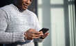 © olezzo - Cute attractive young african american guy in gray sweater using mobile phone internet on city streets