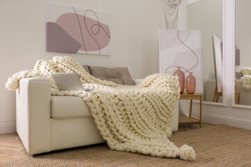 Wall Mural - Soft knitted blanket and modern laptop on couch in living room. Interior element