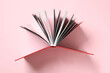 © New Africa - Open book with red cover on pink background, top view