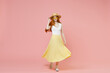 Full length body young nice smiling happy redhead woman 20s ginger long hair wear straw hat glasses summer clothes flow yellow maxi pleated skirt isolated on pastel pink background studio portrait.