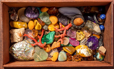 Wall Mural - Gemstone collection in wooden chest, close-up. Mixed rough and tumbled stones, silver rings and pendants. Top view.