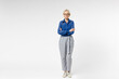 © ViDi Studio - Full length blonde successful confident employee business woman 40s wearing blue classic shirt gray pants glasses formal clothes hold hands crossed folded isolated on white background studio portrait.